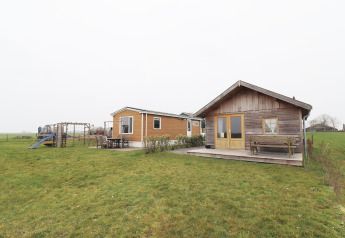 Twee charmante lodges en speeltuin op gras bij Frisian Hideaway with Style in Nederland, bewolkte lucht.