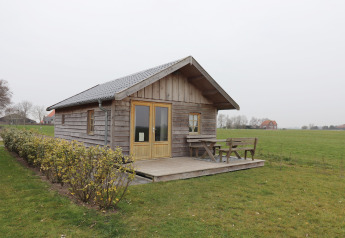 Sfeervol houten huisje, Frisian Hideaway with Style, met terras en bank in een landelijke omgeving.