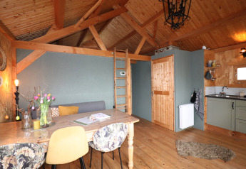 Knus lodge-interieur in Frisian Hideaway met houten plafond, eettafel en compacte keukenhoek.