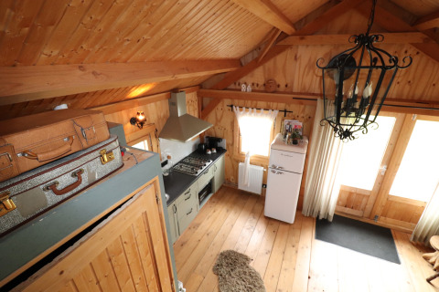 Gezellige houten lodge in Nederland met keuken, retro koelkast, vintage koffers en rustieke sfeer.