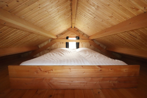 Knusse zolder slaapkamer met houten balken en bed in Frisian Hideaway with Style in Nederland.