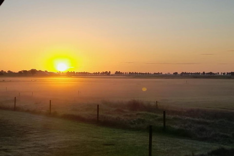 Zonsopgang boven een mistig veld gezien vanaf Frisian Hideaway with Style lodge in Nederland, landelijk.