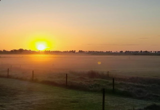 Zonsopgang boven een mistig veld gezien vanaf Frisian Hideaway with Style lodge in Nederland, landelijk.