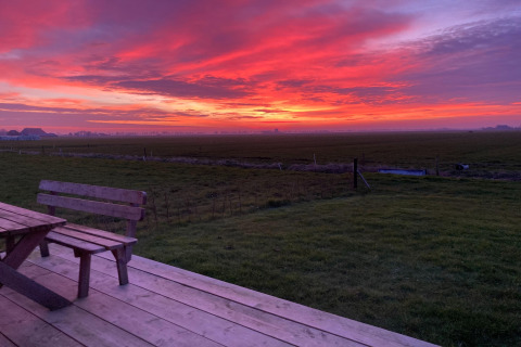 Zonsondergang boven de velden vanaf het terras bij Frisian Hideaway with Style in Nederland.