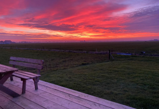 Zonsondergang over velden vanaf het houten terras bij Frisian Hideaway with Style in Nederland.