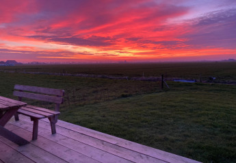 Zonsondergang over velden vanaf het houten terras bij Frisian Hideaway with Style in Nederland.