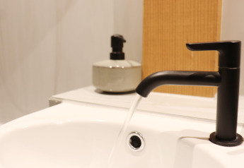 Moderne zwarte kraan met stromend water in de lavabo bij Frisian Hideaway with Style, Nederland.