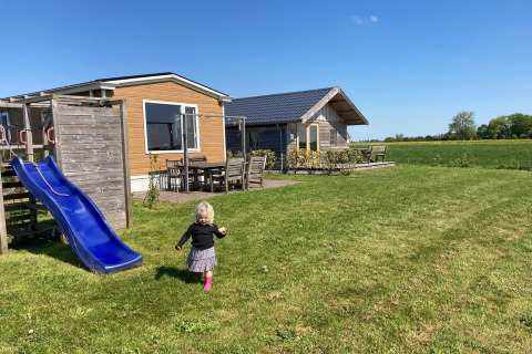Een klein kind speelt op het gras bij een blauwe glijbaan bij Frisian Hideaway with Style in Nederland.