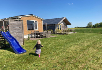 Een kindje speelt op het gras bij een blauwe glijbaan aan het Frisian Hideaway with Style in Nederland.
