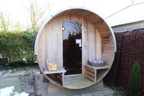 Sauna barril de madera al aire libre en Scenic Stay with en Países Bajos, con bancos y cubeta visible.