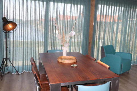 Comedor moderno en Scenic Stay with en los Países Bajos, con mesa de madera y cortinas azules.