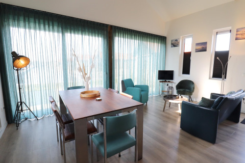 Luminoso y moderno salón-comedor en el lodge 'Scenic Stay with' en Países Bajos, con ventanas grandes y mobiliario elegante.