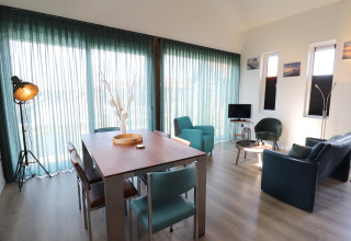 Lys og moderne stue i lodge 'Scenic Stay with', Holland, med spisebord, læderstole og store vinduer.