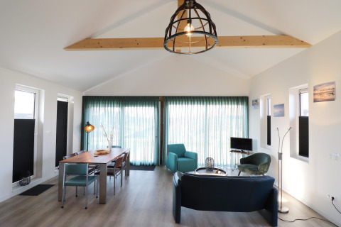Salón moderno y luminoso de lodge en Scenic Stay with, Países Bajos, con vigas de madera y grandes ventanales.