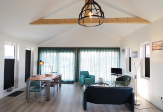 Moderne lodge-stue med træbjælker, store vinduer, spisebord og bløde stole i Scenic Stay with, Holland.