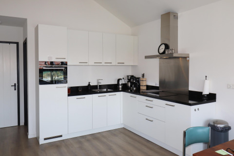 Moderne køkken med hvide skabe, sort bordplade, ovn og komfur, fotograferet i Scenic Stay with i Holland.