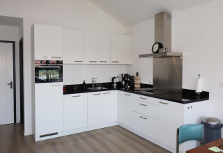 Cocina moderna con armarios blancos y encimeras negras, fotografiada en Scenic Stay with en los Países Bajos.