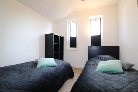 Værelse med to enkeltsenge, sorte dyner og lyseblå puder på Scenic Stay with i Holland, moderne indretning.