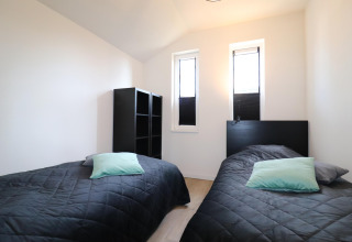 Dormitorio con dos camas individuales, colchas negras y cojines menta en Scenic Stay with en Países Bajos, decoración moderna.