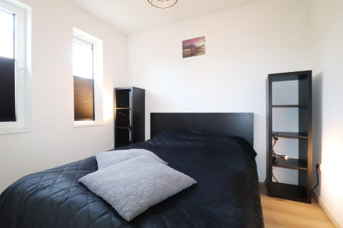 Moderne soveværelse på 'Scenic Stay with' i Holland med sort seng, hylder og to store vinduer.