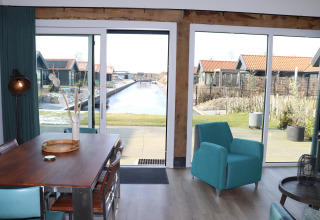 Udsigt fra lodge 'Scenic Stay with' i Nederlandene, moderne interiør med kanaludsigt gennem store vinduer.