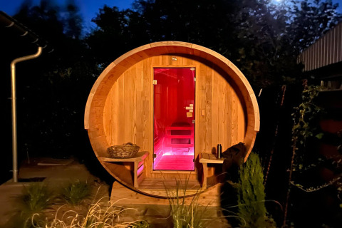 Rund trætønde sauna med rød belysning i nattemiljø, ved logiet 'Scenic Stay with' i Holland.