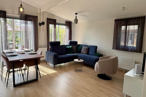Stilfuld stue og spisestue i Chalet nær Sint Maartenszee Strand i Holland, med moderne møbler og store vinduer.