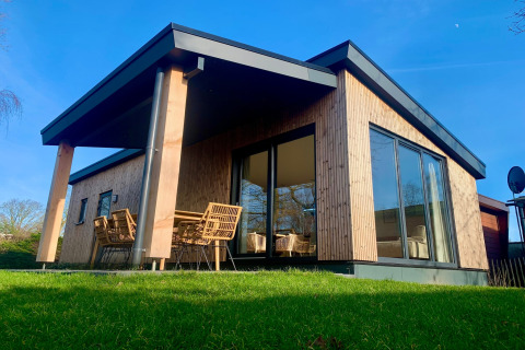 Chalet moderno a Sint Maartenszee vicino a Sandy Beach, con grandi finestre e posti a sedere fuori.