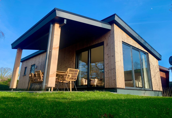 Chalet moderno a Sint Maartenszee vicino a Sandy Beach, con grandi finestre e posti a sedere fuori.