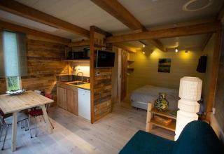 Interior acogedor de un chalet en Sint Maartenszee, Países Bajos, con cama, cocina y comedor de madera.