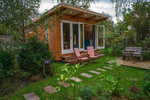 Sfeervol chalet in Sint Maartenszee, strandhuis met groene tuin en comfortabele buitenzitjes.