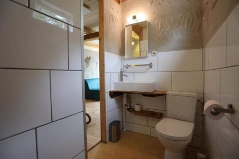 Moderne badkamer met witte tegels, wc en wastafel in een strandchalet in Sint Maartenszee, Nederland.