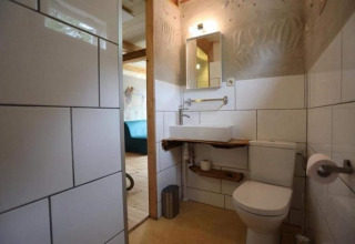 Moderne badeværelse med hvide fliser, toilet og håndvask i et strandhus i Sint Maartenszee, Holland.