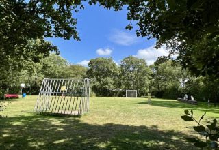 Pelouse verte avec enfants jouant, deux buts et arbres près d’un chalet aux Pays-Bas.