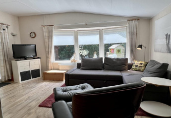 Wohnzimmer eines kleinen Familienchalets nahe dem Strand in den Niederlanden mit Sofa und TV.
