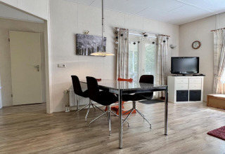 Helles Wohnzimmer in einem kleinen Familienchalet nahe dem Strand in den Niederlanden mit Esstisch und Fernseher.