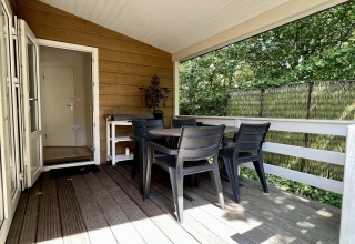 Overdekt terras met tafel en stoelen bij een klein familiechalet vlakbij het strand in Nederland.