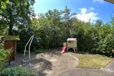 Jardin adapté aux enfants d’un petit chalet familial près de la plage aux Pays-Bas, avec maisonnette et toboggan.
