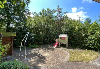 Kindvriendelijke tuin bij een klein familiechalet dicht bij het strand in Nederland, met speelhuisje.