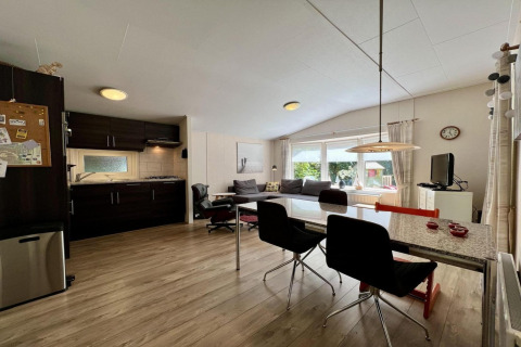 Woonkamer en keuken in een klein familiechalet vlakbij het strand in Nederland, moderne inrichting.