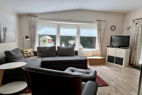 Woonkamer in een klein familiechalet dicht bij het strand in Nederland met bank en televisie.