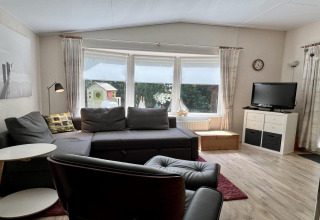 Soggiorno di un piccolo chalet familiare vicino alla spiaggia nei Paesi Bassi con divano e TV.