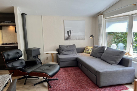 Moderne woonkamer in een klein familiechalet vlakbij het strand in Nederland met een grijze hoekbank.