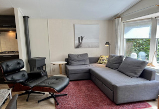 Sala de estar moderna en un pequeño chalet familiar cerca de la playa en los Países Bajos con sofá gris.