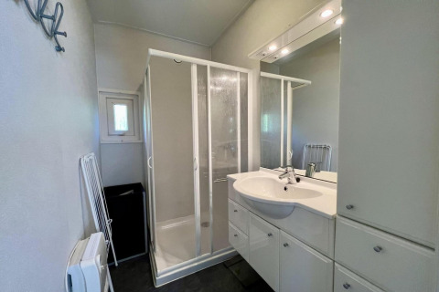 Baño en pequeño chalet familiar cerca de la playa en Países Bajos con cabina de ducha y muebles blancos.