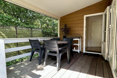 Overdekt terras bij Small family chalet close to beach in Nederland met tafel en vier stoelen buiten.