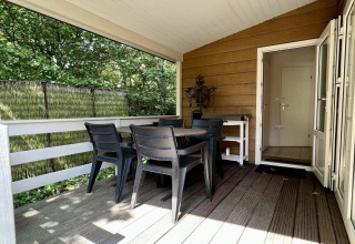 Overdekt terras bij Small family chalet close to beach in Nederland met tafel en vier stoelen buiten.
