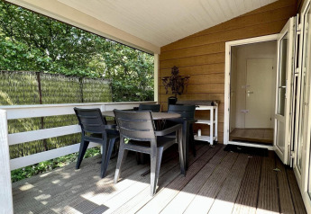 Overdækket terrasse ved Small family chalet close to beach i Holland med spisebord og fire stole.