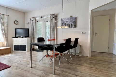 Salon lumineux d'un petit chalet familial près de la plage aux Pays-Bas, avec table à manger et télévision.