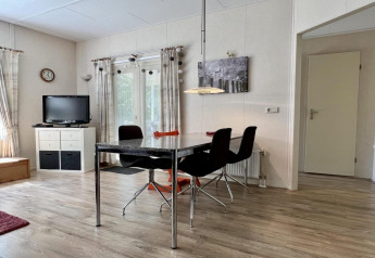 Helles Wohnzimmer im kleinen Familienchalet nahe dem Strand in den Niederlanden mit Esstisch und TV.